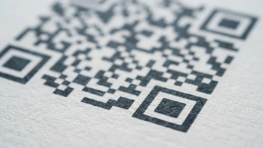 Primer plano de un código QR impreso en papel, con sus patrones de posición y módulos en detalle